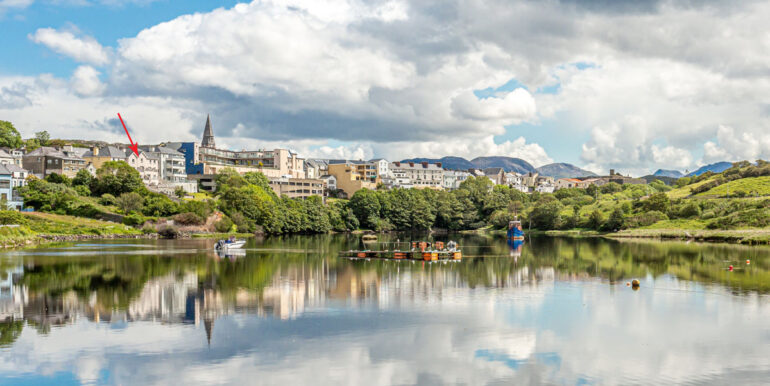Clifden harbor at high tide with clouds reflecting in the water and the village in the background