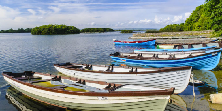 Rowing boats filled with water sit moored up at an Irish lough (lake)